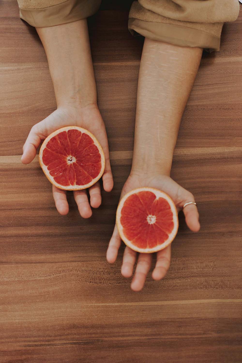 woman holding grapefruits on both hands