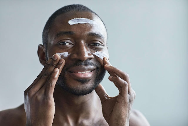 man is using his skincare, adding moisturizer on his face