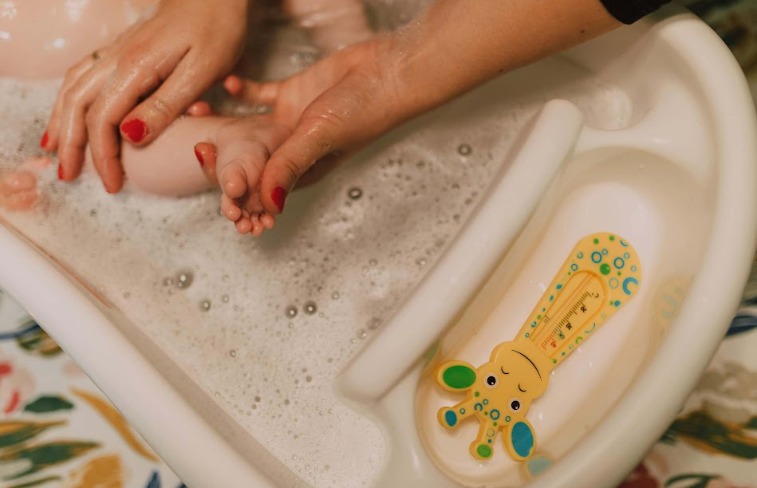 Mother washing the baby feet using baby wash