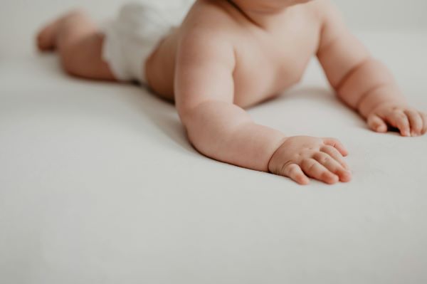 a baby lying on the white bed with a healthy skin